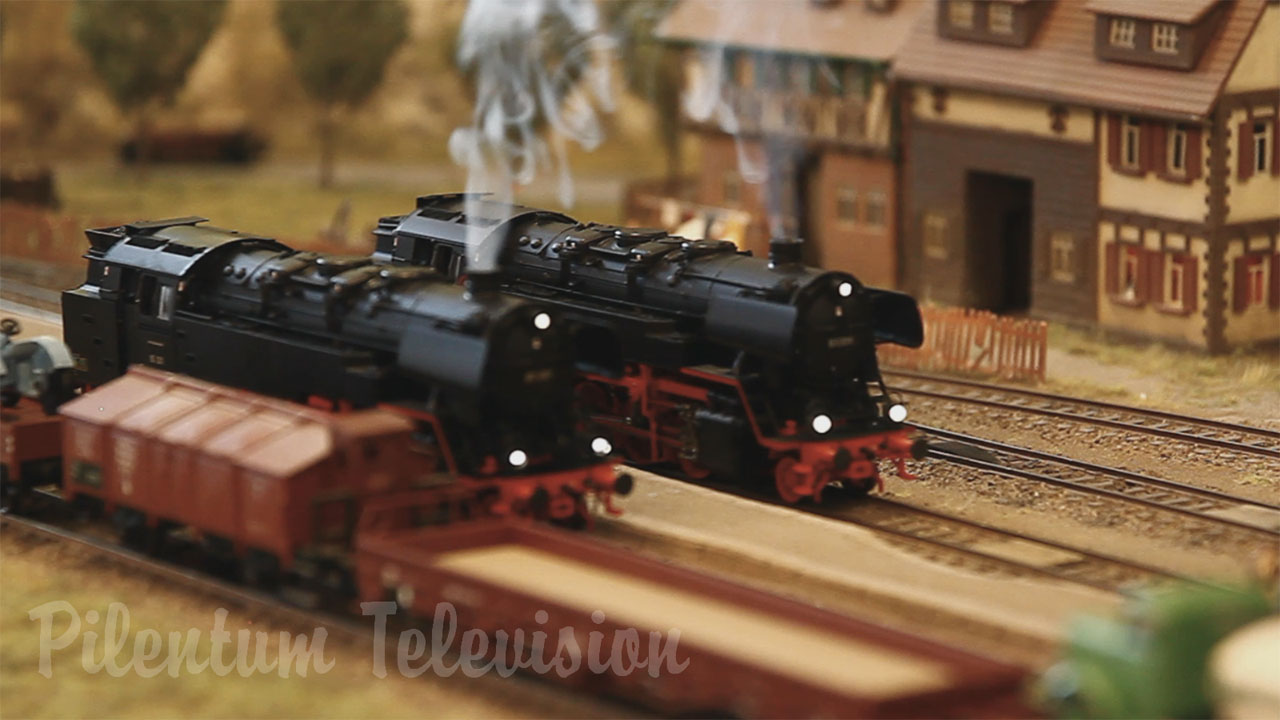 Une jolie maquette de train à l’échelle HO avec des locomotives à vapeur qui fument